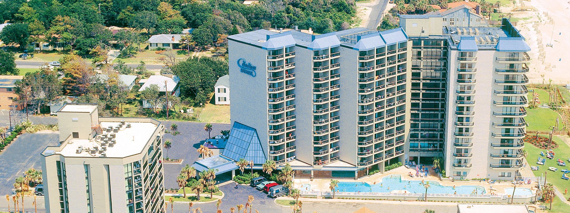 Aerial view of a large hotel with a pool and parking lot.